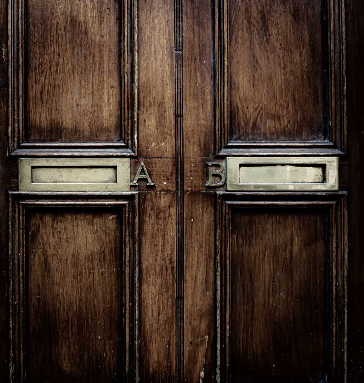 An antique door with two mail slots side by side labeled 