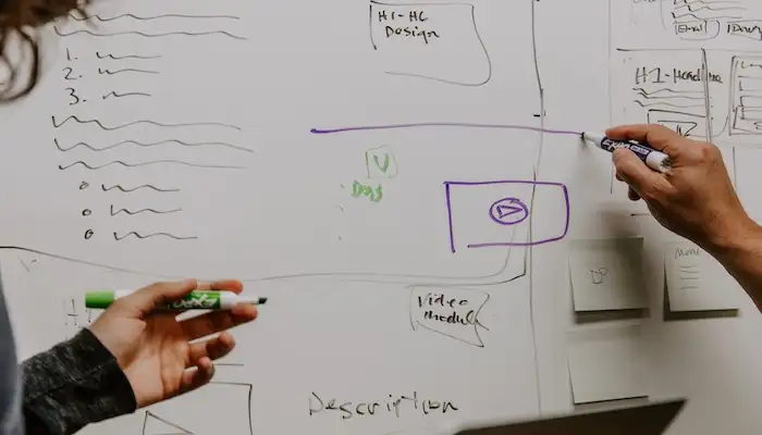 two people drawing plans on a whiteboard