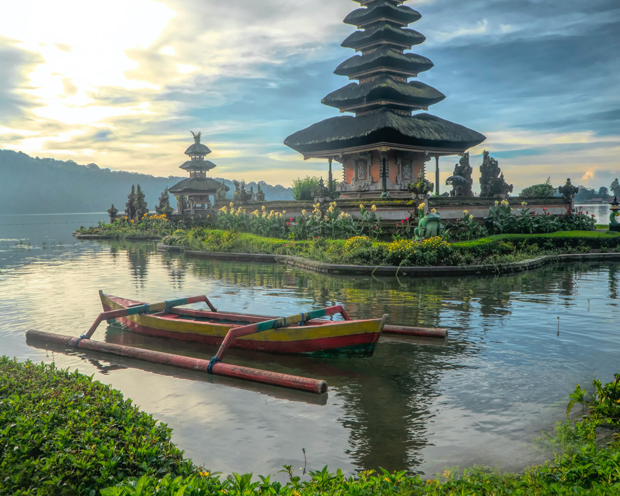 boat on the water in bali with green island and temple in background