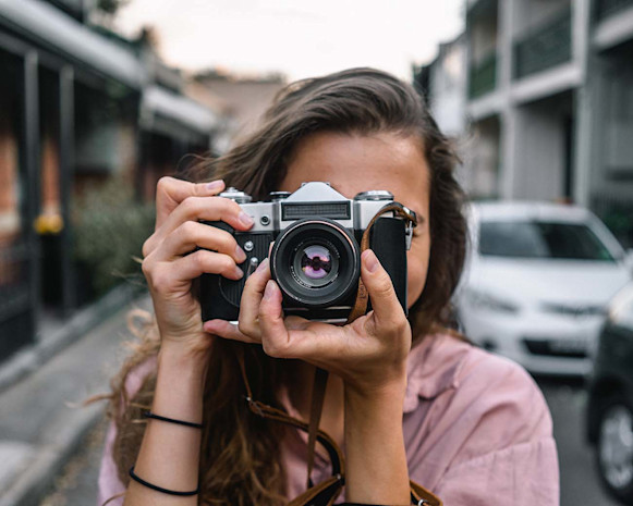 woman holding black and silver camera and adjusting the lens