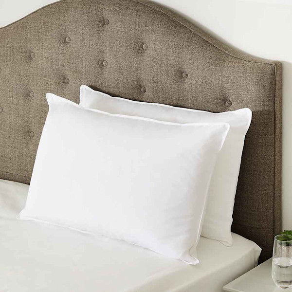 two white pillows against a grey headboard