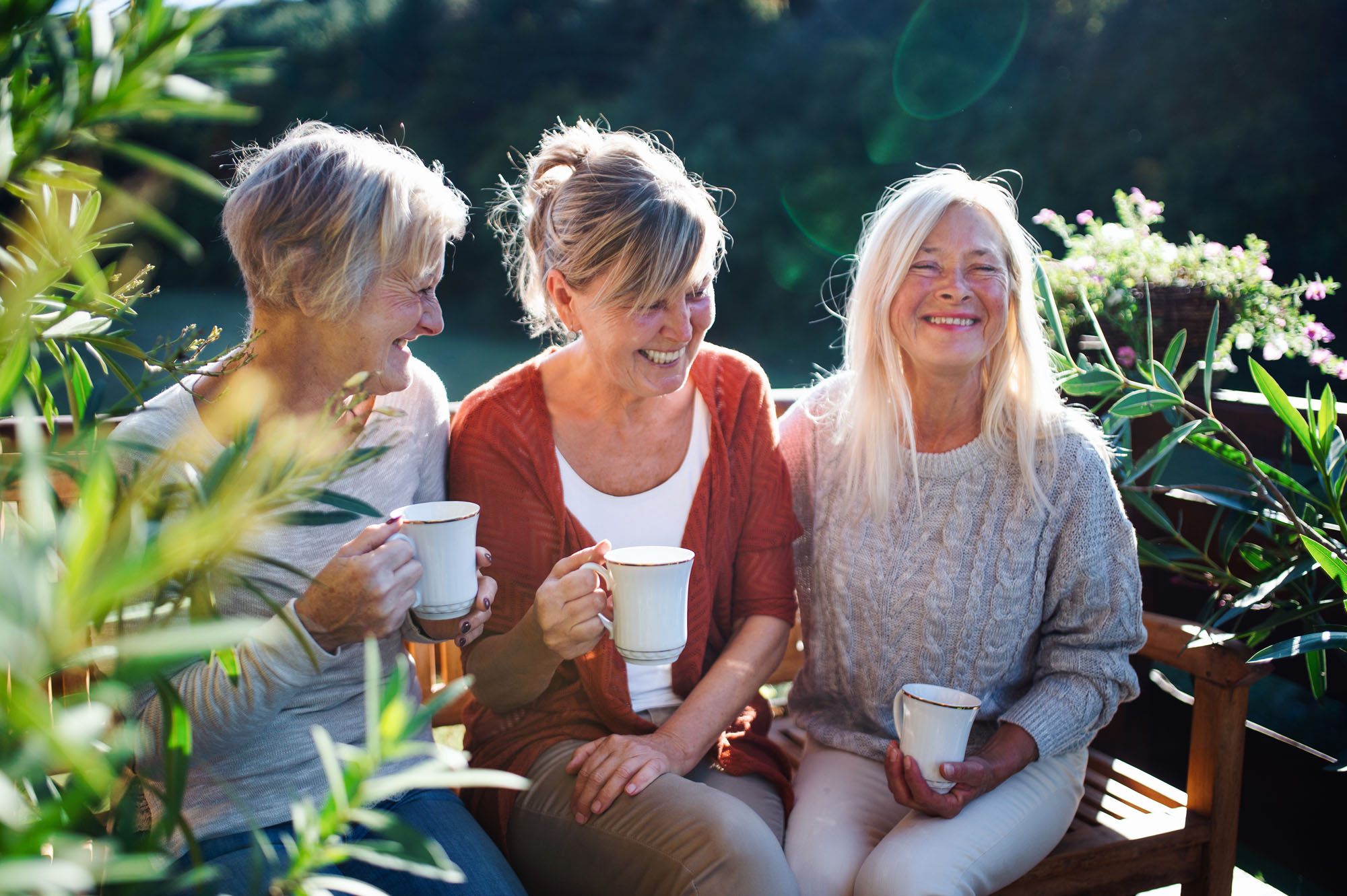 3 women having coffee on a bench