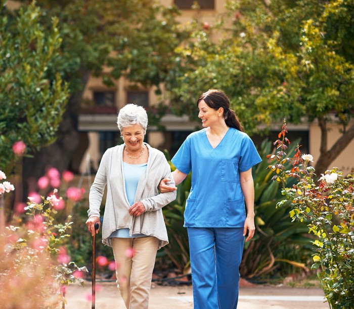 A nurse walking with a woman in a garden