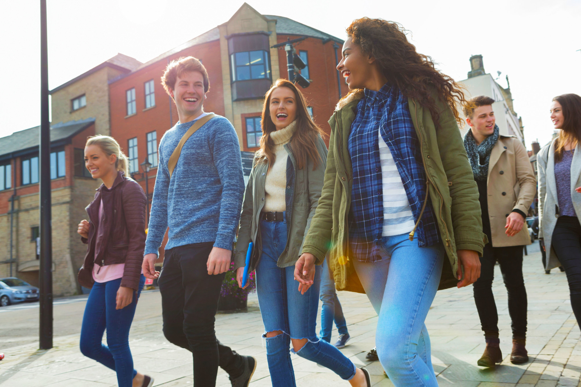 A group of young people walking on a sidewalk