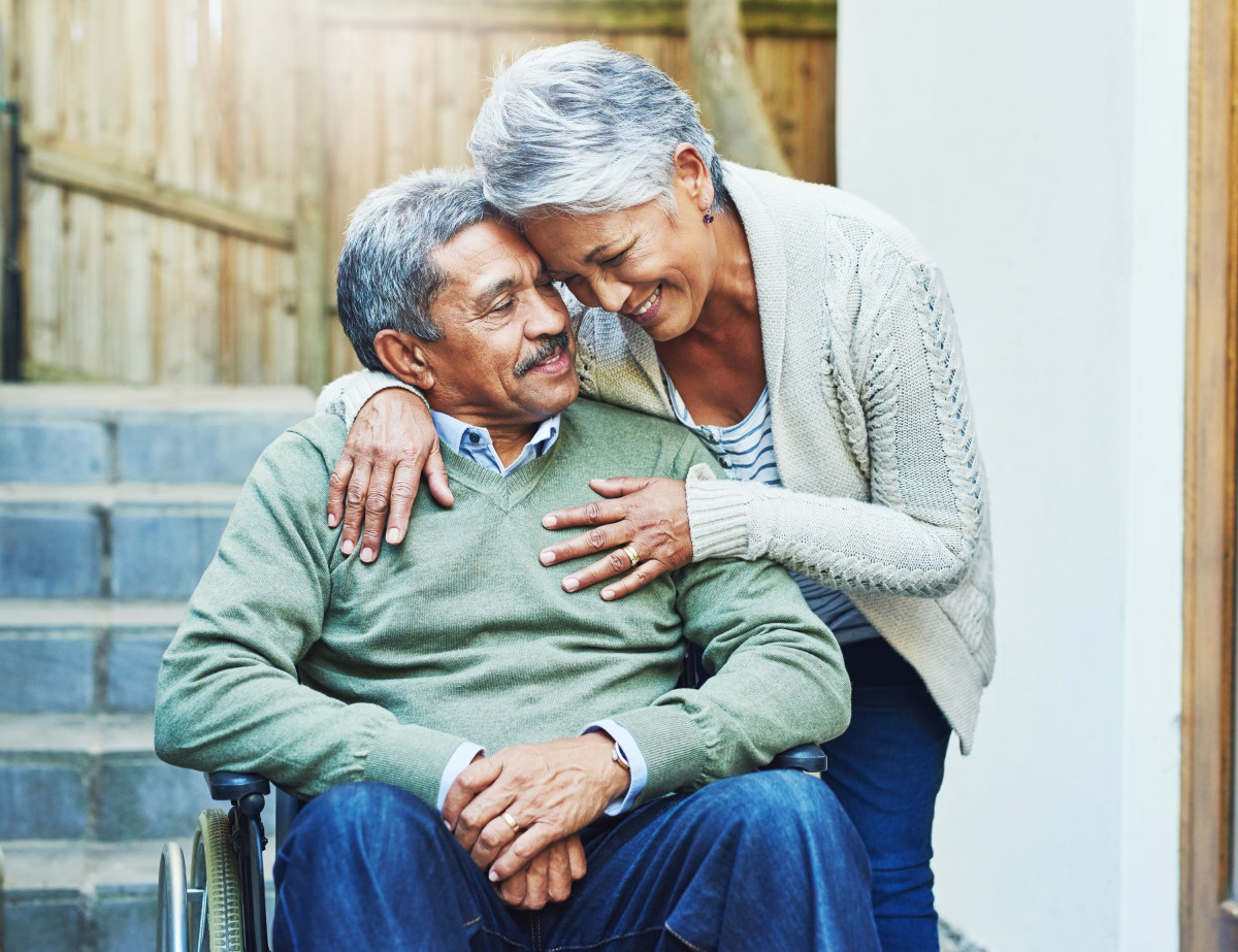 A woman hugging a man in a wheelchair