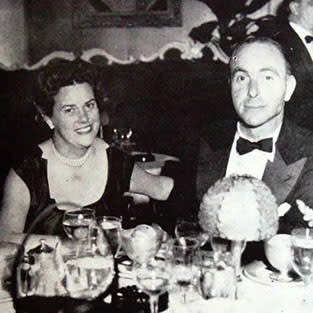 Vintage black and white photograph of a couple at a fancy dinner.