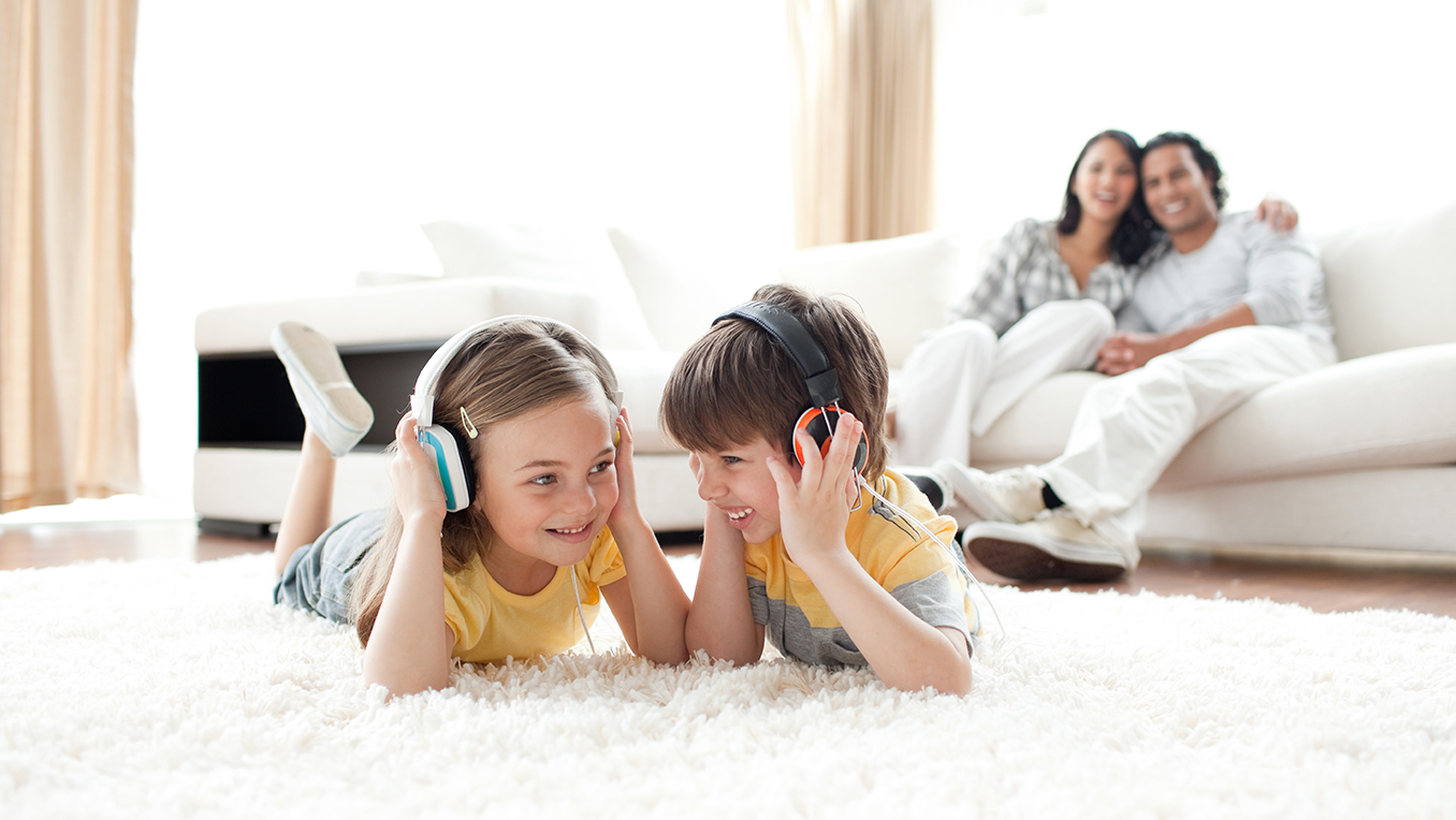 Enfants heureux à la maison avec des écouteurs pendant que les parents relaxent