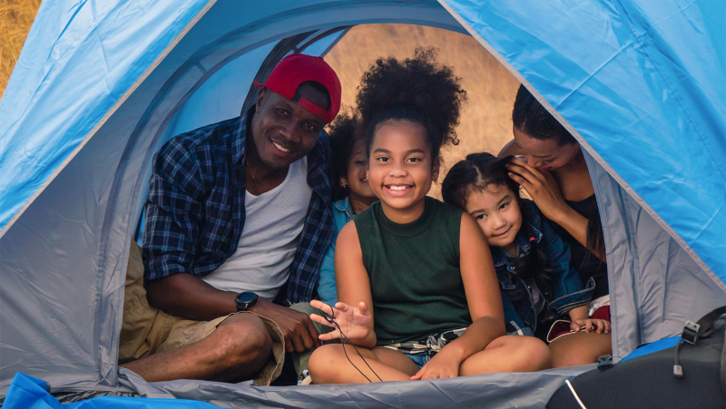 African-American family smiling inside a tent at a campground