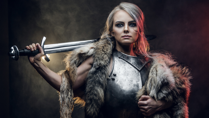 A young woman dressed as a Viking in armor and furs, with a sword over her shoulder