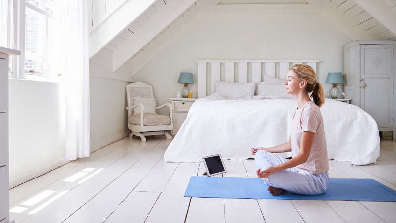 Femme pratiquant la méditation à la maison en écoutant des livres audio