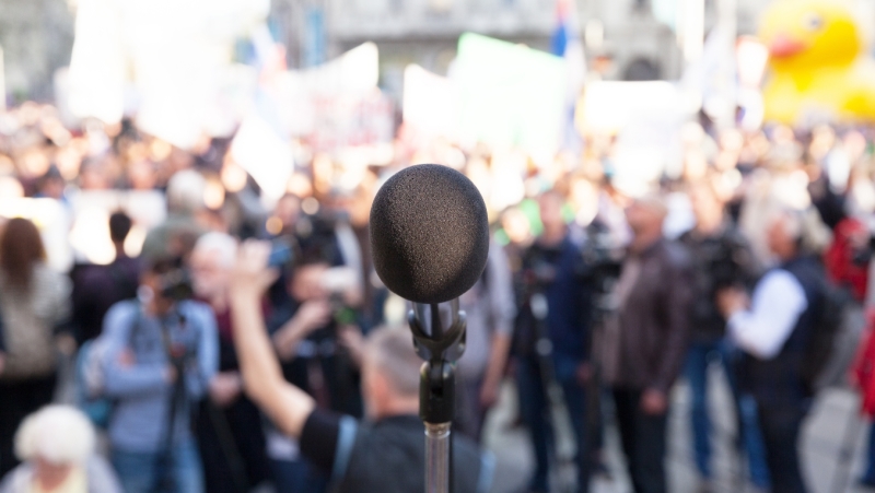 A photo of a political rally with a microphone in the foreground