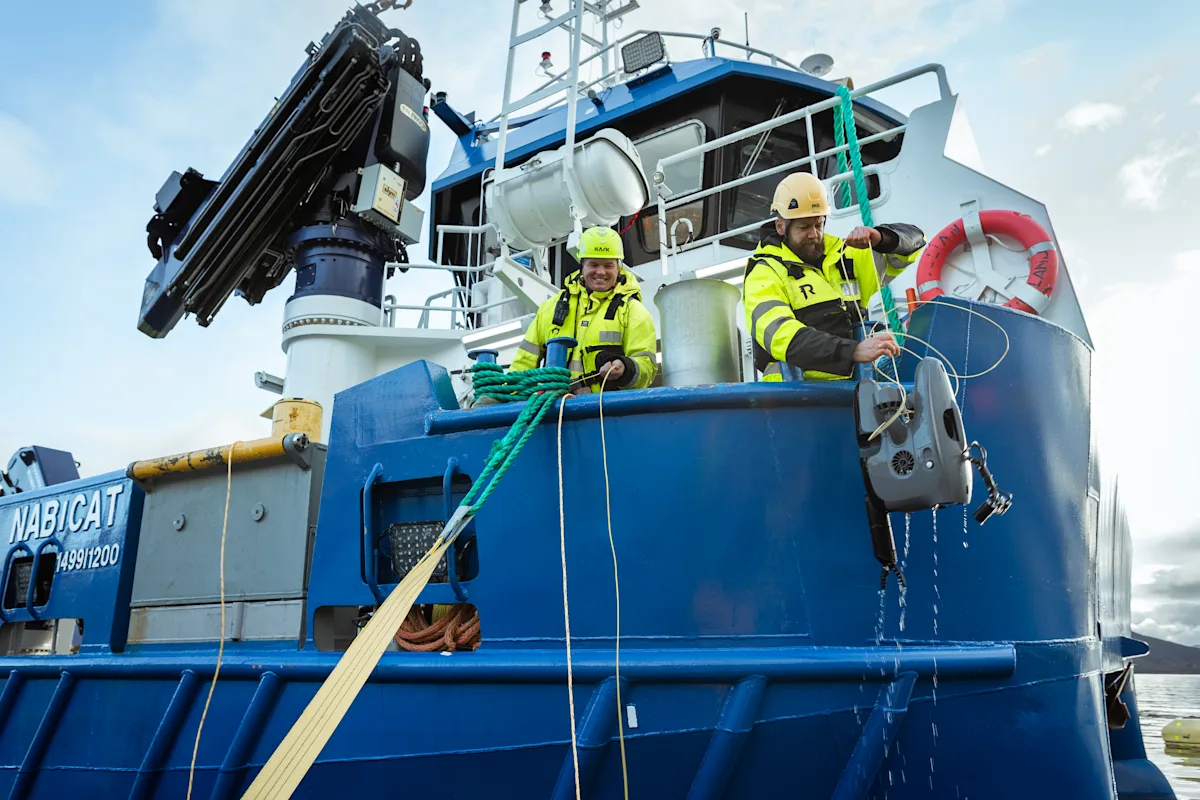Person pulls the underwater drone up from the fish farming boat