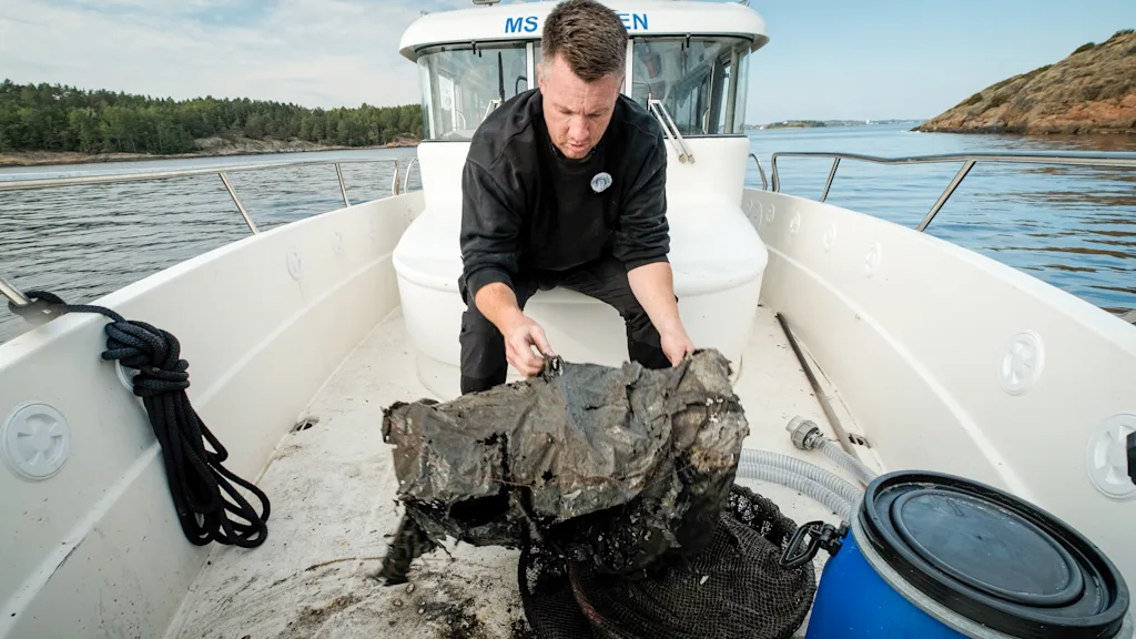 Arild Karlsen lifts a mud-covered piece of recovered fishing gear
