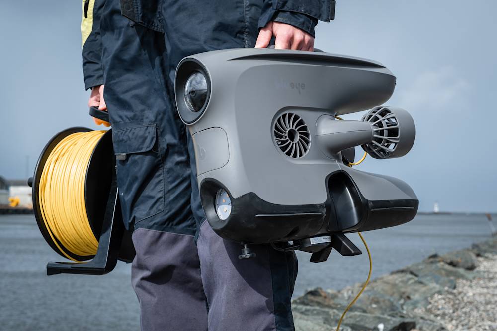 Person holding X3 with DVL and tether reel