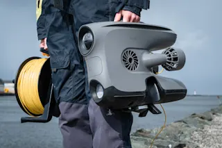 Person holding X3 with DVL and tether reel