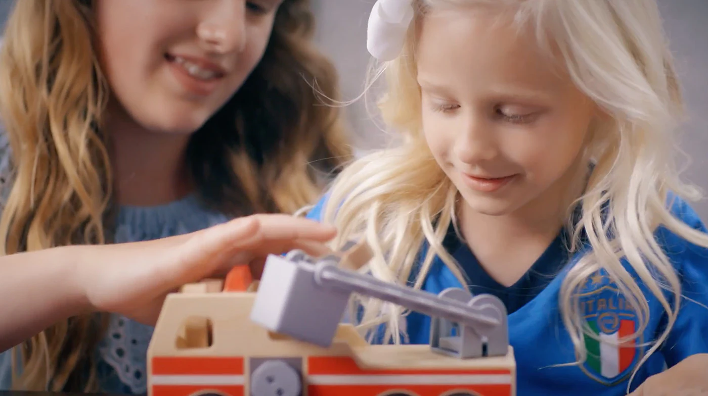 Image of two girls playing with a fire truck. 