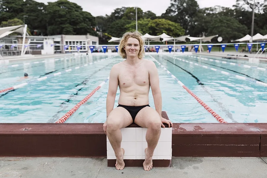 Young man sitting on edge of swimming pool 2