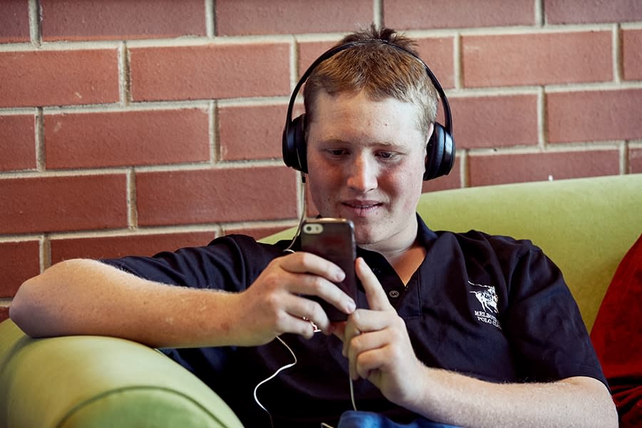 teenage boy wearing headphones looking at phone