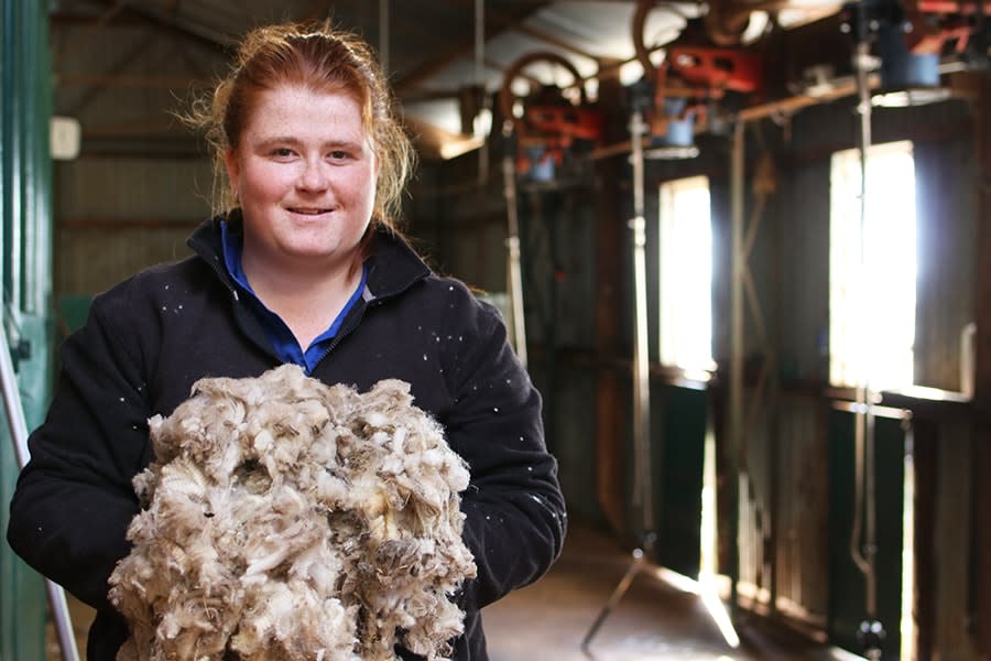 BrandiLea girl holding wool with processing equipment behind her