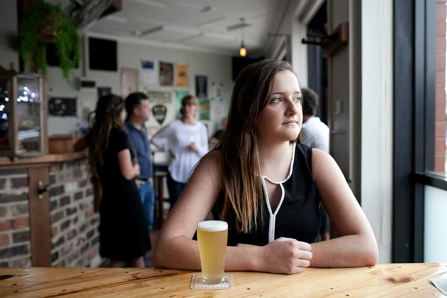 girl with beer looking out pub window