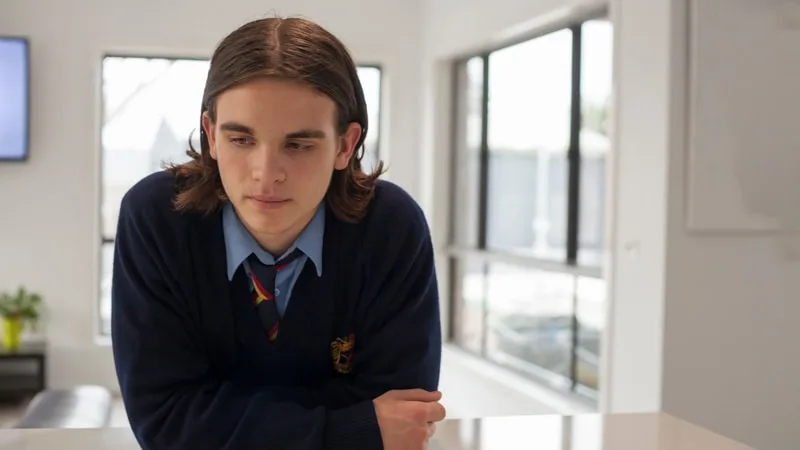 a teenager standing at a kitchen table