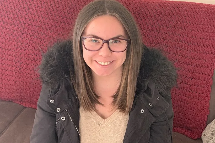 young woman with brown hair wearing glasses smiling