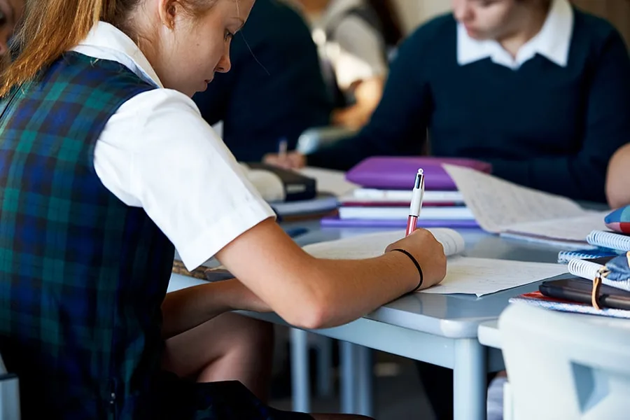 back angled side view of school girl writing on paper