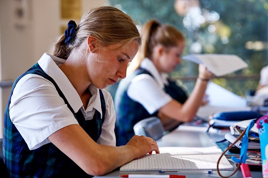 girl in school uniform in classroom looking at exercise book