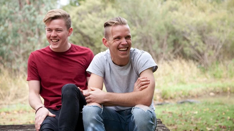 two boys sitting next to each other and smiling