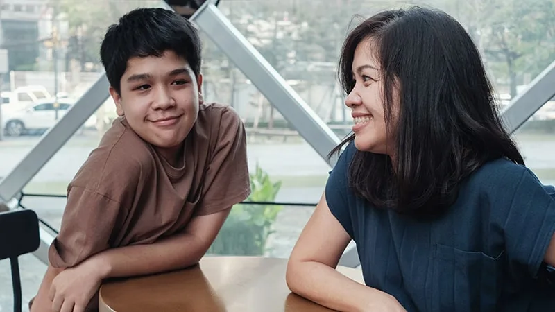 mother and son talking at table