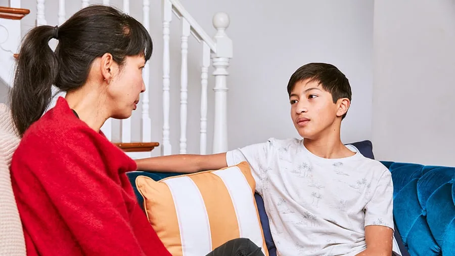 mum and teenage boy sitting on couch chatting (1)