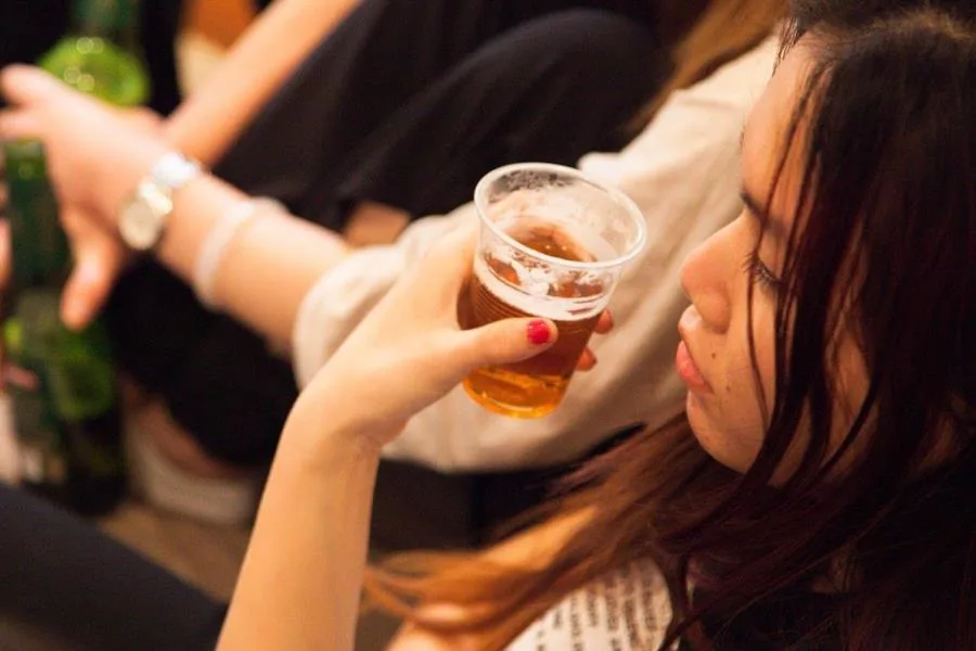 aerial view of girl holding plastic cup of beer