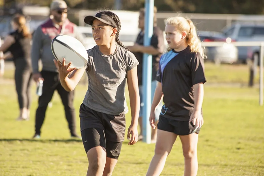 two girls in grass field holding football