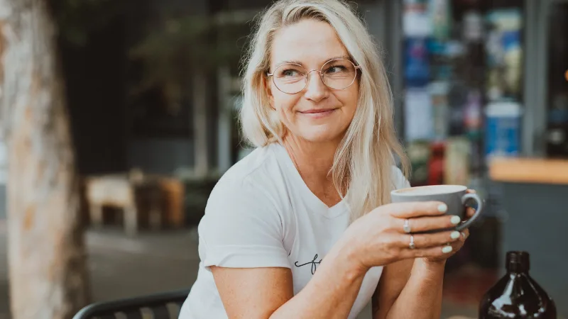 Jayne McCartney sitting down and drinking coffee