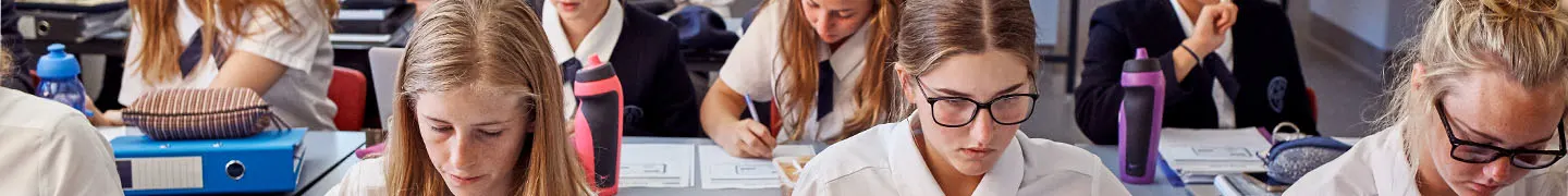 students sitting in a classroom looking down at their school work