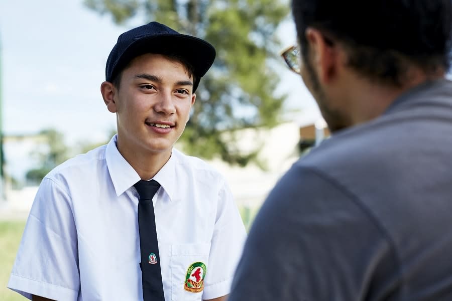 Close up of boy with hat talking to youth worker