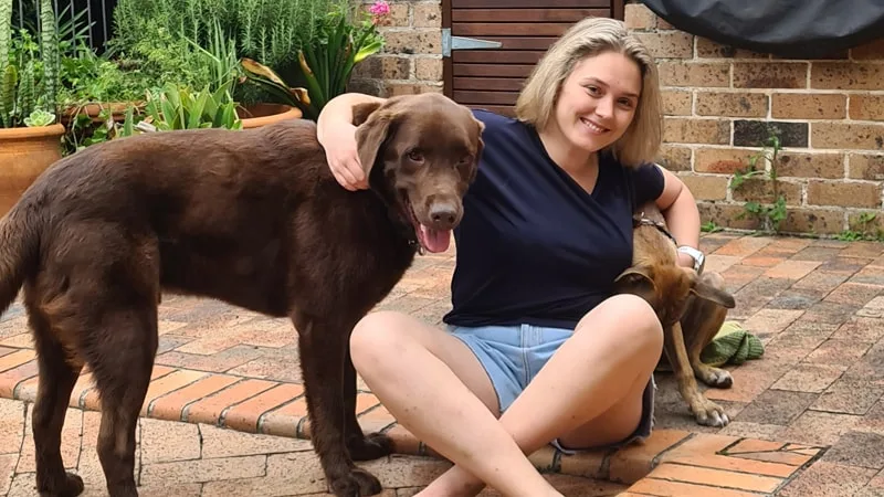 Sian sitting down in her backyard with her dogs