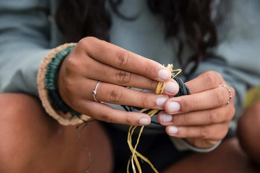 Close-up of an Aboriginal girl's hands as she is preparing threads for weaving baskets and bracelets.