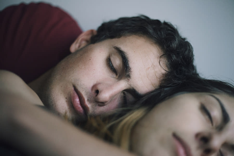 Image of a teen boy and girl laying in bed, asleep.