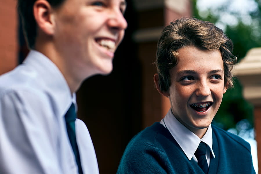 Image of two teens boys laughing at something off camera.