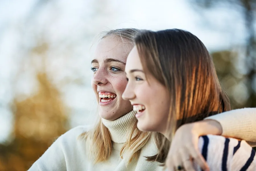 two girls smiling with arms around each other