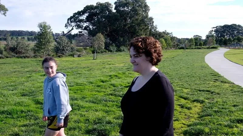 a mother and daughter walking in a park