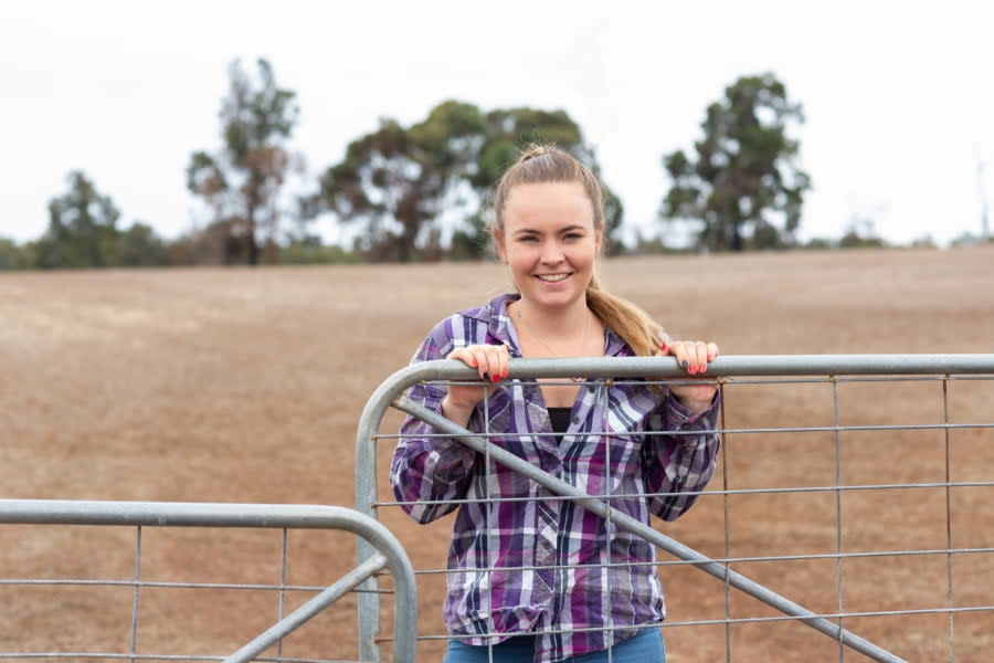 A young woman in rural Australia closing a gate on her farm