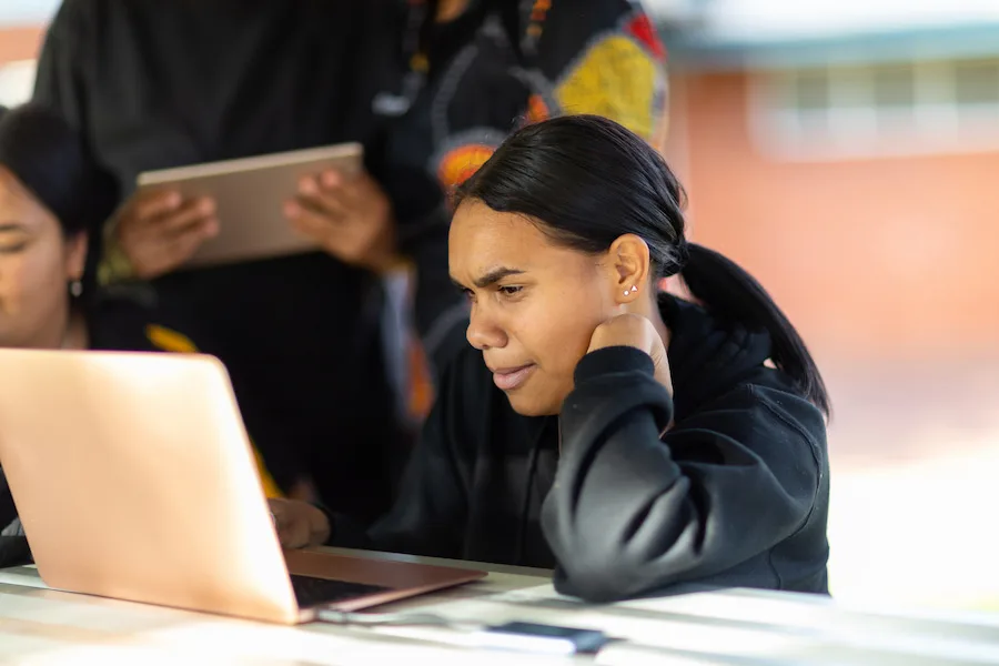 Young Indigenous woman sitting outside on her computer