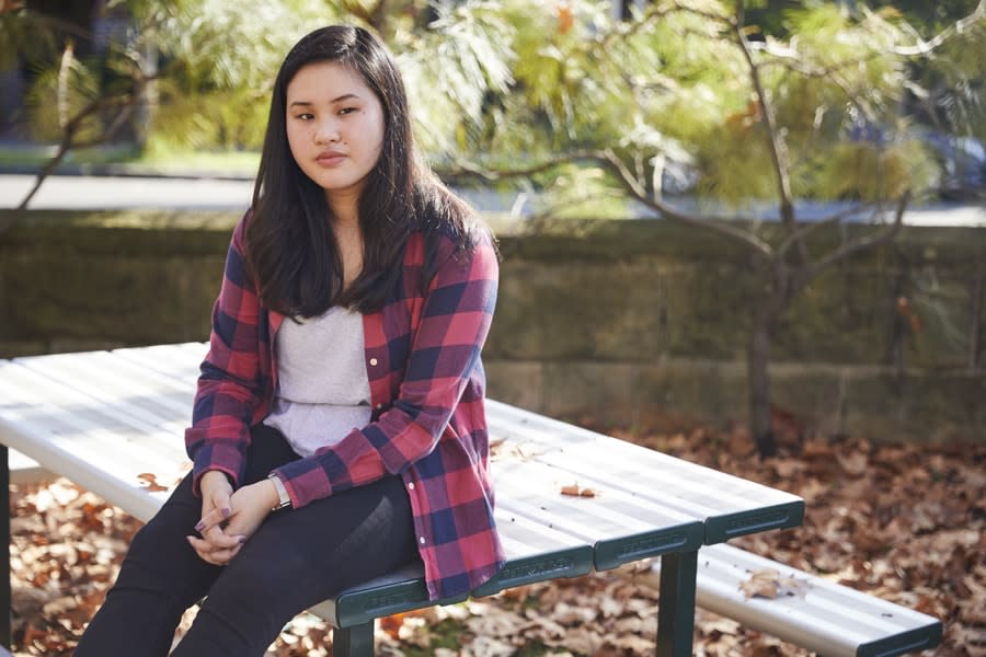 A young person sitting on a picnic table outside. 