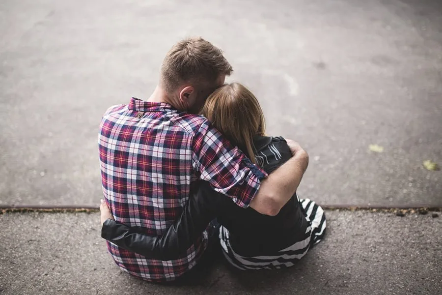 Man in red hugging woman in stripes