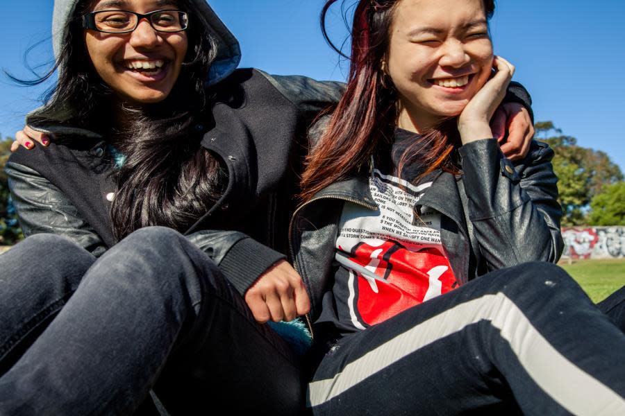 two girls laughing in park with arms around each other