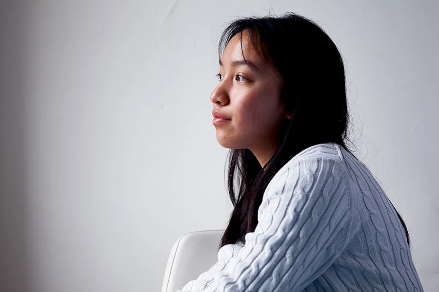 Image of a teen girl looking away from the camera, towards a window in her bedroom.