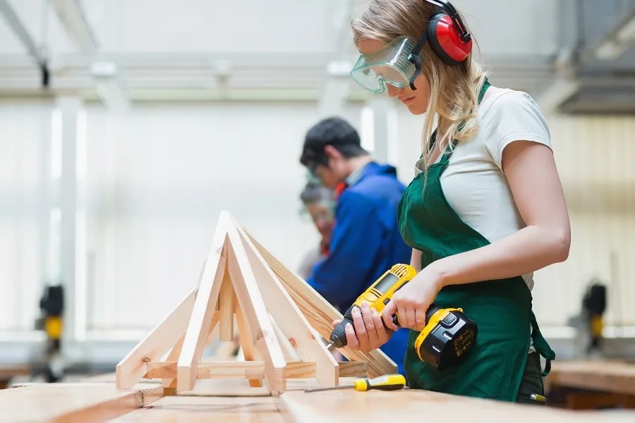 Girl with green apron in woodwork class