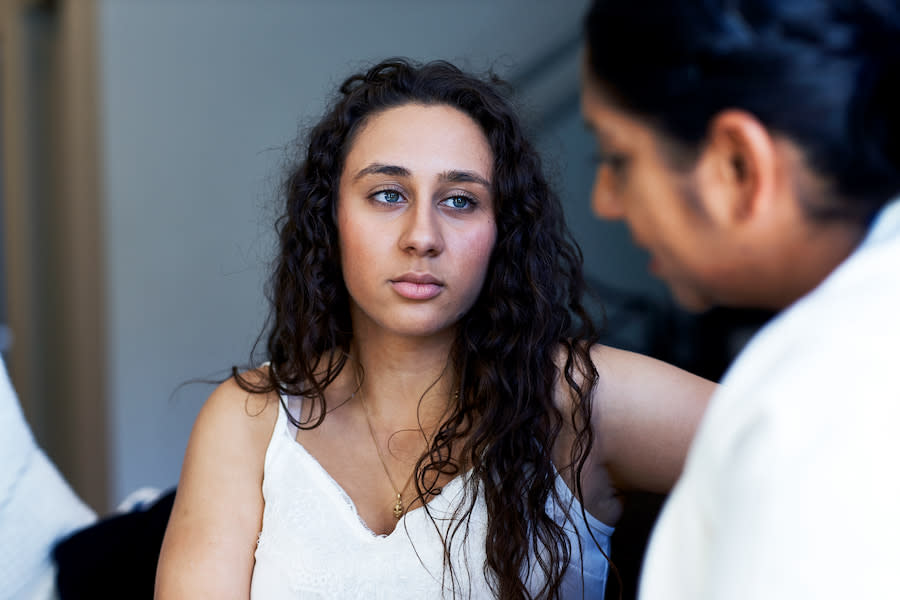 Image of a teenage girl with a neutral expression listening to her mother talk.